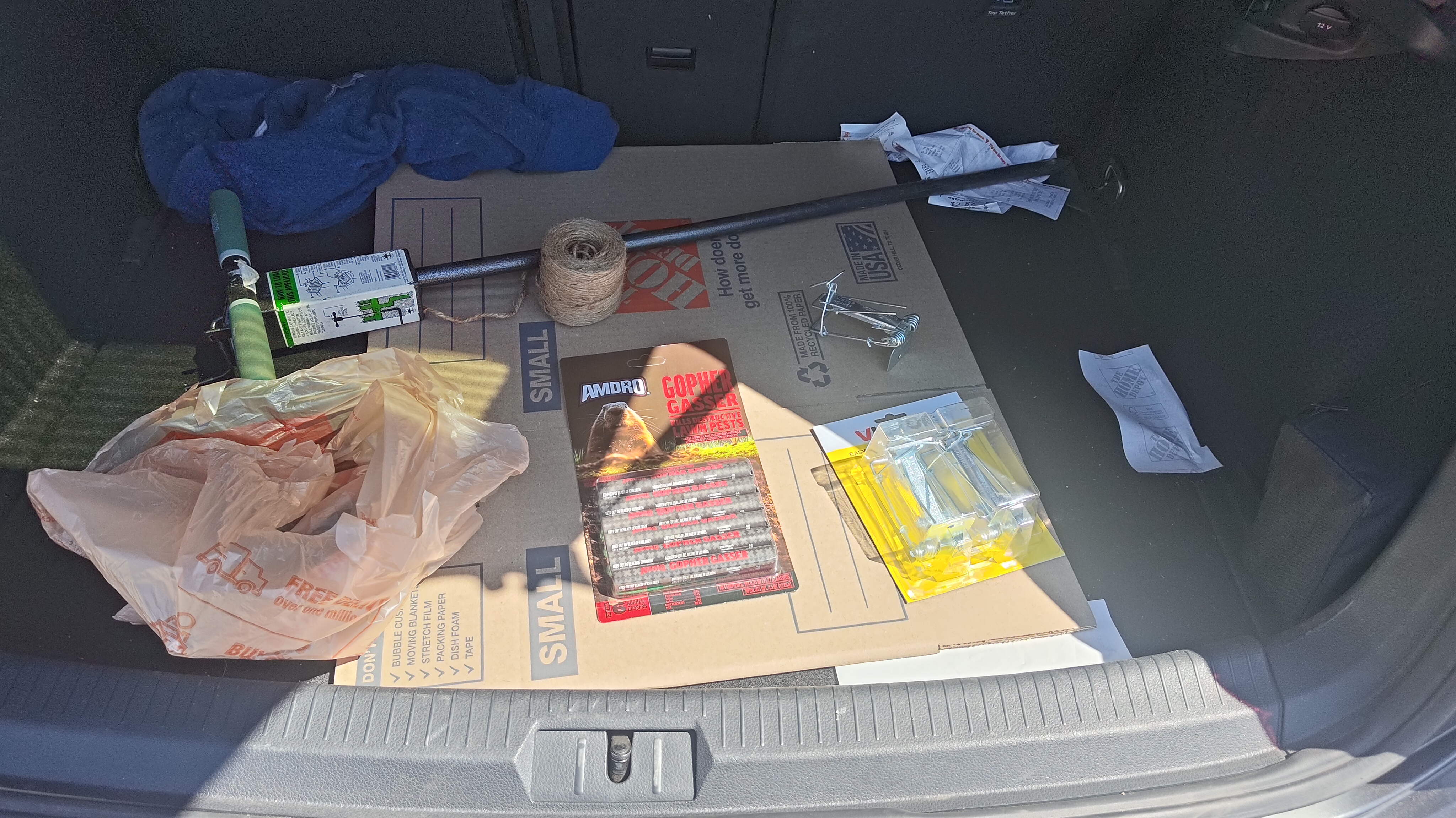 Mark's full gopher control kit laid out in a car trunk — Victor traps, Amdro gopher gassers, probe, twine, and cardboard